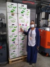 A representative of Inter-Faith Food Shuttle Standing next to a pallet of Soap Saves Lives Box Hygiene Kits