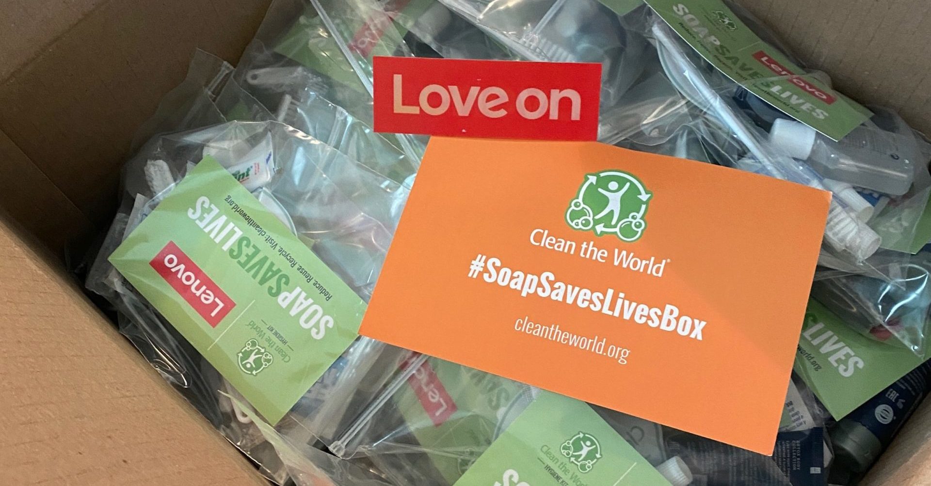 A Soap Saves Lives Box full of Hygiene Kit. On top of the hygiene kits is a notecard that says "Love On"